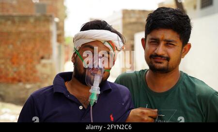 Jaipur, India - Maggio 2021: Giovane uomo infettato con la malattia di Corona Virus. Maschera per l'inalazione di ossigeno con flusso di ossigeno liquido. Ospedale Concept Foto Stock