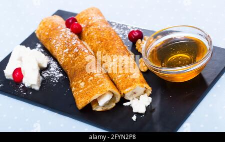 Frittelle squisitamente servite farcite con formaggio giovane e miele Foto Stock