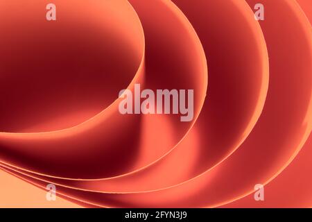 Sfondo macro colorato astratto, creato con fogli di carta aranciati arancioni. Linee e forme curve e colori tenui e vivaci. Foto Stock