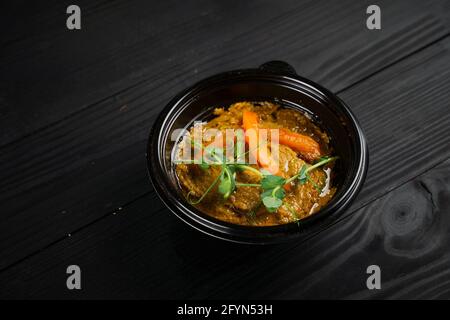 Hummus guarnito con peperoni ed erbe in piastra nera sopra tavolo di legno scuro Foto Stock