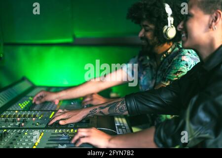 Giovani che lavorano insieme al pannello di controllo nella registrazione musicale studio Foto Stock