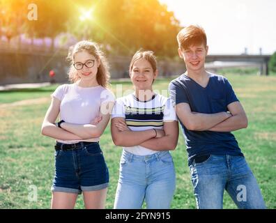 Ritratto di tre ragazzi felici e sicuri nel parco cittadino nella soleggiata giornata estiva Foto Stock