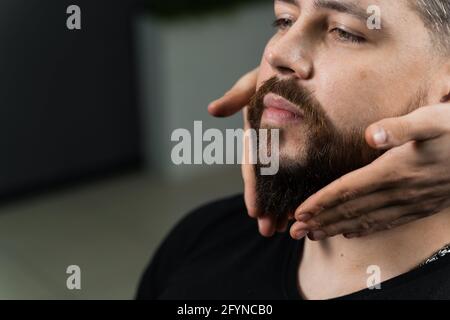 Fissaggio della forma della barba con cera. Il risultato di un taglio di capelli in un barbiere Foto Stock