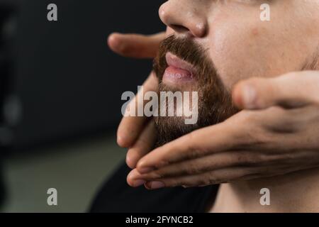 Fissaggio della forma della barba con cera. Il risultato di un taglio di capelli in un barbiere Foto Stock