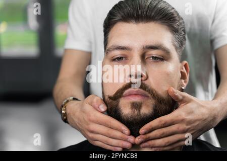 Fissaggio della forma della barba con cera. Il risultato di un taglio di capelli in un barbiere Foto Stock