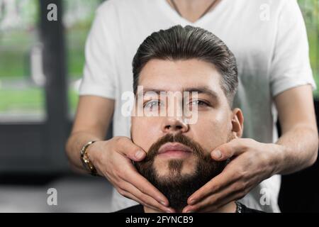 Fissaggio della forma della barba con cera. Il risultato di un taglio di capelli in un barbiere Foto Stock