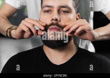 Fissaggio della forma dei baffi con cera. Il risultato di un taglio di capelli in un barbiere Foto Stock