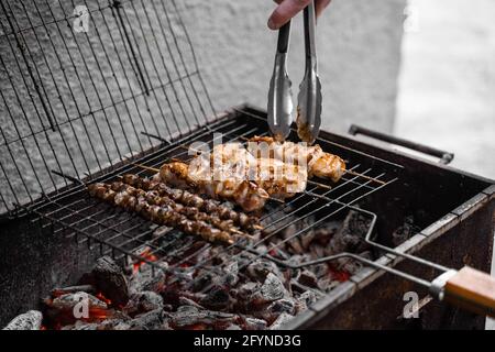 Carne grigliata su spiedini di legno su griglia di metallo su carbone. Cottura di pollo, cuori Foto Stock
