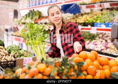 Un'assistente amichevole del negozio femminile sta aiutando ad acquistare arance al supermercato Foto Stock