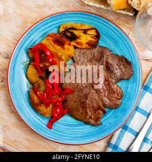 Bistecche di manzo mediamente rare con contorno vegetale di patate al forno e peperone Foto Stock