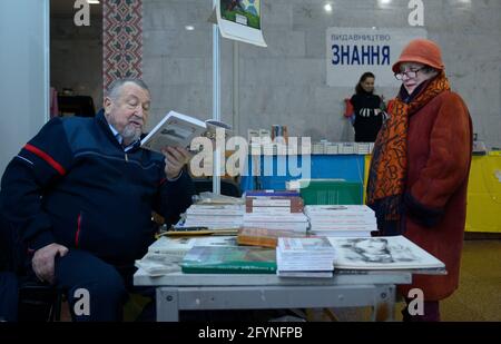 Il produttore dell'uomo presenta il suo libro che lo legge ad un cliente anziano della donna. Prenota Fiera Knyzhkovyi Arsenal . 24 maggio 2019. Kiev, Ucraina Foto Stock