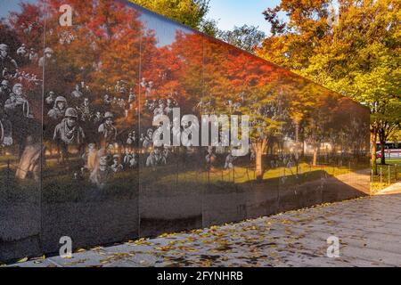 Le immagini fotografiche dei soldati e degli alberi autunnali si riflettono nella parete di granito nero altamente lucidato del memoriale di guerra coreano, Washington DC Foto Stock