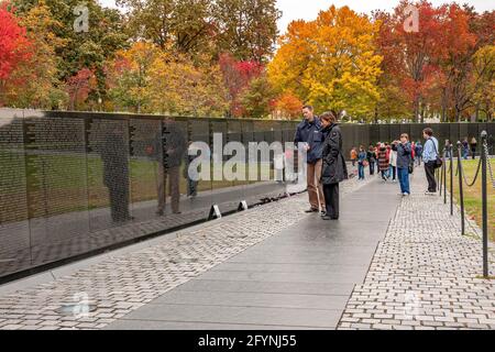 Una coppia legge i nomi inscritti nel memoriale dei veterani del Vietnam che onora le forze armate statunitensi che hanno combattuto nella guerra del Vietnam, Washington DC Foto Stock