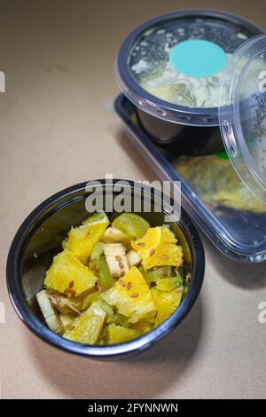 Insalata di frutta con ananas e banana in un contenitore. Consegna di cibo. Foto Stock