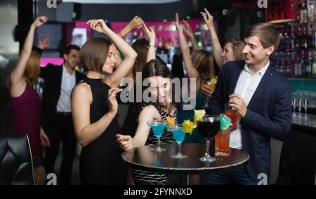 Felice felice positivo ai colleghi che danzano sul partito aziendale con un cocktail in mano Foto Stock