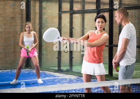 Ritratto di allenatore professionista concentrato insegnando giovane giocatore giocando padel indoor Foto Stock