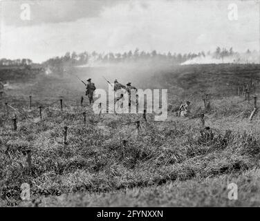 LA PRIMA GUERRA MONDIALE: TRUPPE BRITANNICHE. I soldati britannici del 107° reggimento di fanteria corrono attraverso il filo spinato su un campo di battaglia vicino Beauquesne, nella regione della Somme in Francia, durante la prima guerra mondiale. Fotografia, 13 settembre 1918. Foto Stock