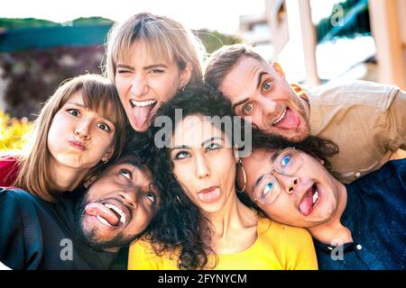 Persone multietniche mileniali che prendono selfie attaccando la lingua con volti felici - stile di vita divertente e concetto di integrazione Foto Stock