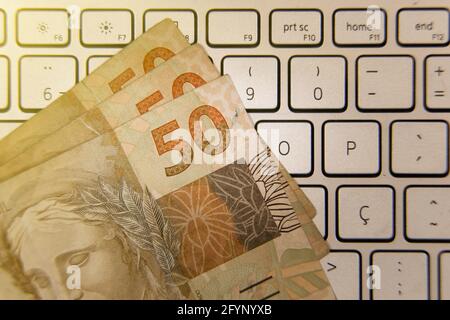 Banconote reali brasiliane - cinquanta banconote reais sulla tastiera di un computer. BRL in Brasile. Concetto di valuta, economia e affari. Foto Stock