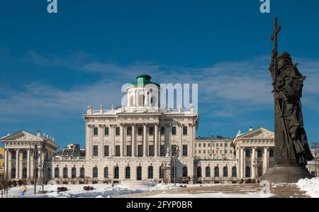 Vista dell'elegante edificio neoclassico della Casa di Pashkov sulla collina di Vagankovsky a Mosca con monumento a Vladimir Great in primo piano nella soleggiata giornata invernale Foto Stock