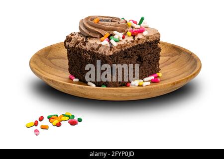 Rainbow spruzzi la guarnizione su panna torta di spugna di cioccolato in piastra di legno isolata su sfondo bianco con percorso di ritaglio. Foto Stock