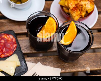Due bicchieri di vermouth rosso fortificato tradizionalmente guarniti con spicchi d'arancia serviti con tapas spagnole. Aperitivo popolare Foto Stock