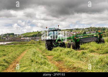 Timoleague, West Cork, Irlanda. 29 maggio 2021. In una giornata colma ma secca e umida con il Frate Francescano Timoleague che domina lo sfondo, Míchael McCarthy, azienda casearia con suo fratello Richard, taglia un campo di erba per insilato con un trattore Deutz-Fahr Agrotron K610 e un rasaerba John Deere 1360. Credit: AG News/Alamy Live News Foto Stock