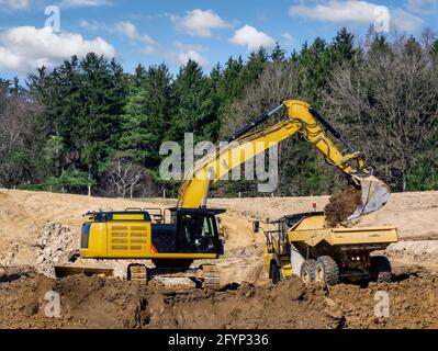 Falda terra gialla che riempie un autocarro in un cantiere Foto Stock