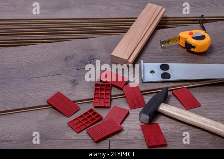 Tavole di pavimento laminato e attrezzature o attrezzi per installarli, martello, palanchino, distanziatori e misuratore con spazio di copia per il testo. Messa a fuoco selettiva. Foto Stock