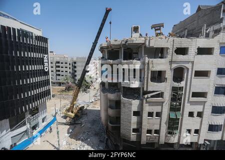 Gaza, territori palestinesi. 29 maggio 2021. Le attrezzature pesanti vengono utilizzate per demolire un edificio distrutto durante gli attacchi aerei israeliani della scorsa settimana nella città di Gaza. Israele e il movimento islamista palestinese Hamas hanno finora mantenuto un cessate il fuoco concordato, che è entrato il 21 maggio venerdì dopo 11 giorni di scontri mortali. Credit: Mohammed Talatene/dpa/Alamy Live News Foto Stock