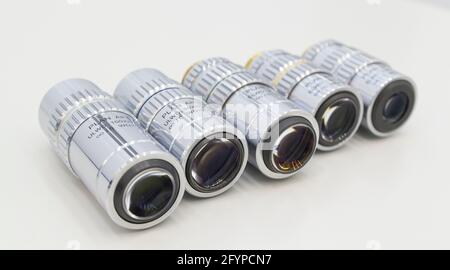 Molti obiettivi sono diversi dall'ingrandimento su sfondo bianco. Primo piano degli obiettivi del microscopio. Foto Stock