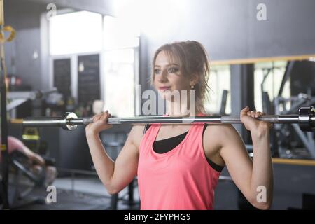 Allegro giovane sportswoman facendo Barbell premere esercizio al palestra Foto Stock