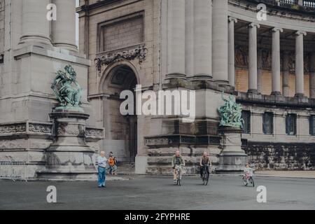 Bruxelles, Belgio - 17 agosto 2019: La gente passa in bicicletta oltre la base dell'Arco di Trionfo nel Parc du Cinquantenaire, parco del XIX secolo a Bruxelles che è il hom Foto Stock