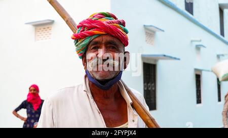 15 maggio 2021 - Reengus, Sikar, India. L'uomo indiano invecchiato con baffi del manubrio indossa un turbano Rajasthani rosso e verde e pone per la macchina fotografica. Foto Stock