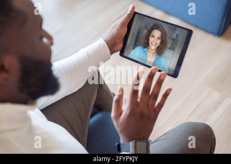 Vista posteriore di un uomo afro-americano che effettua una videochiamata con donna rimanere a casa Foto Stock