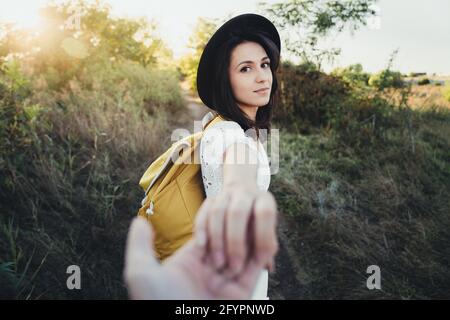 Donna escursionista che tiene la mano dell'uomo e lo conduce sulla natura all'aperto. Coppia innamorata. Scatto punto di vista Foto Stock