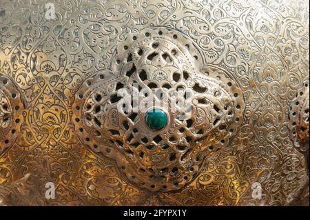 Un esempio di motivi artistici su metallo. Frammento di un oggetto metallico con un inserto di pietra turchese.sfondo. Foto Stock
