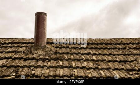 Camino sul tetto di una vecchia casa. Tetto di ardesia. Foto Stock