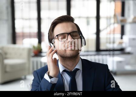 Un dipendente tranquillo e felice in cuffia che ascolta musica rilassante Foto Stock