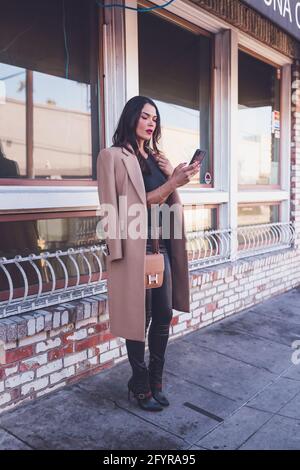 Donna di affari che guarda il suo telefono sul marciapiede. Foto Stock