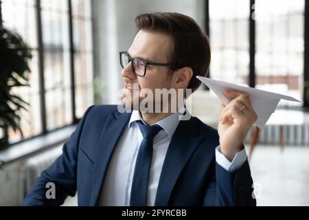 Felice pensieroso leader di affari che tiene e getta aeroplano di carta Foto Stock