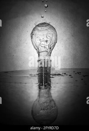 Immagine verticale in scala di grigi di una lampadina con gocce d'acqua Foto Stock