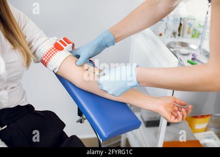 Laboratorio e analisi del sangue. Primo piano di un'infermiera professionista in guanti, che preleva un campione di sangue dalla vena del braccio di una giovane donna Foto Stock