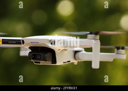 Primo piano di un drone volante contro uno sfondo verde sfocato Foto Stock