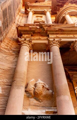 Vista ad angolo basso di colonne con capitelli corinzi sulla facciata del Tesoro, al-Khazneh, rilievi raffiguranti gli dei greci Dioscuri, petra, giordania Foto Stock