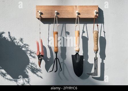 Gli attrezzi da giardinaggio appesi al molo di legno Foto Stock