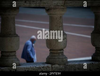 Arezzo, 28 maggio 2021, antiche colonne in pietra con un anziano gentiluomo dai capelli bianchi che passeggiano sullo sfondo sfocato Foto Stock