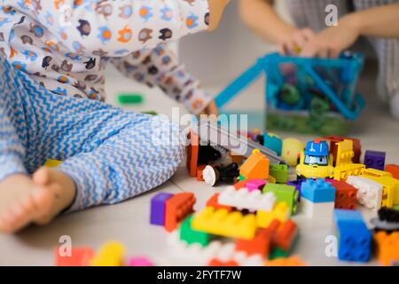 bambino ragazzo che gioca con sua madre in kit di costruzione per bambini a colori. I dettagli del kit di costruzione per bambini sono sparsi sul pavimento. Foto Stock