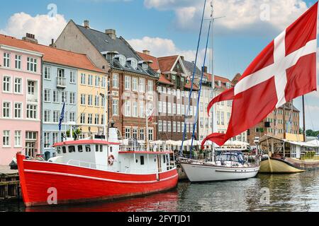 Nyhavn un porto del 17 ° secolo a Copenaghen con case e barche colorate tipiche con bandiera nazionale della Danimarca sul primo terreno. Foto Stock