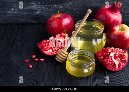 Miele, melograno e mele rosse su fondo nero Foto Stock